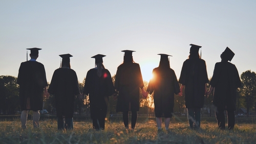 Silhouettes,Of,College,Graduates,Standing,In,A,Meadow.